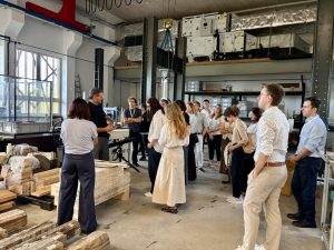 A group of people stand and listen to a tour guide in the InnoRenew CoE building in the Composites Laboratory.